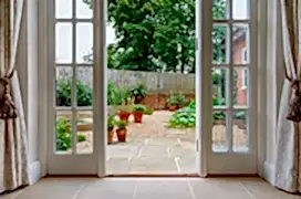 View of garden from inside house with French doors leading to a courtyard kitchen garden.
