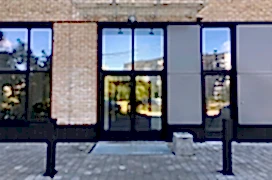 Modern real estate, residential apartment building, entrance with glass canopy and door.