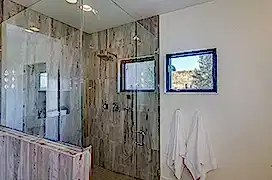 Dark gray tile in shower and white towels nearby
