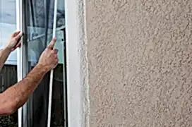 Man cleaning window of a home and installing a screen.