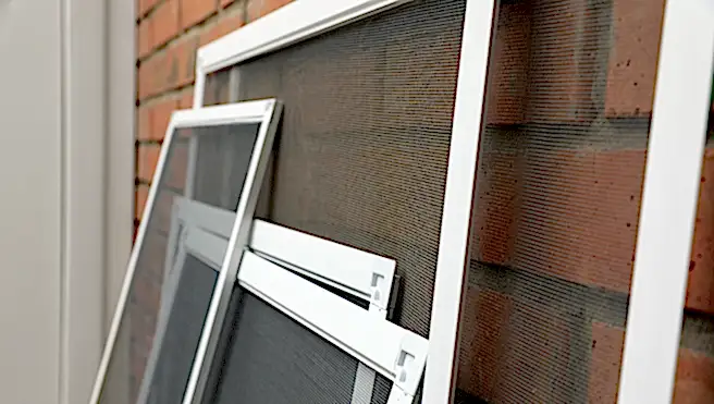 Set of window screens near brick wall.
