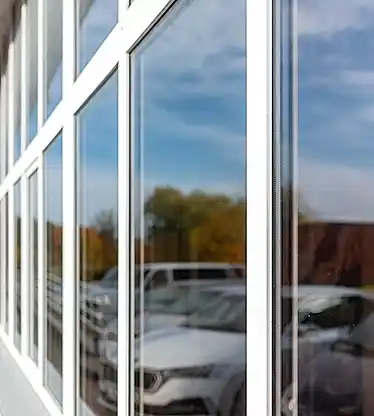 Office building or apartment house with cars parking reflection on a cloudy summer day.