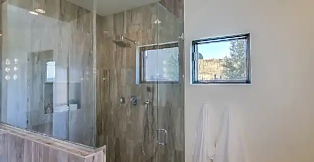 Dark gray tile in shower and white towels nearby.