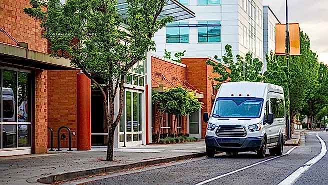 White fleet van on an empty, tree-lined street